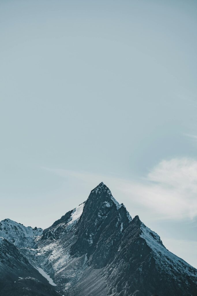A stunning snow-capped mountain peak against a clear blue sky, showcasing nature's beauty.