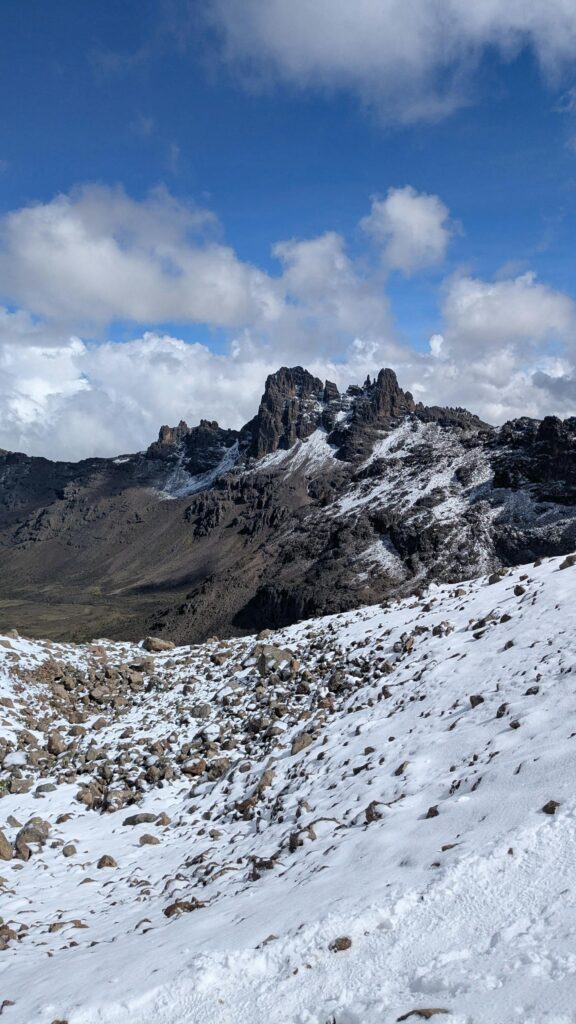 Majestic view of Mount Kenya's rocky peaks covered in snow with a clear blue sky backdrop.
