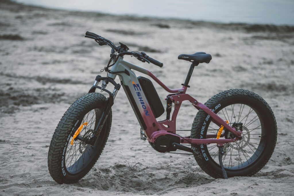 Electric bicycle with fat tires parked on a sandy beach, symbolizing modern outdoor transportation.